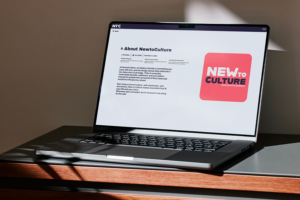 A laptop resting on a desk showing the About NewToCulture website interface and red brand logo.